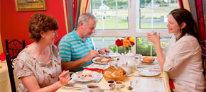 Man and two women eating a meal at a table in a bed and breakfast