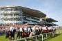 Group of jockeys pass in front of stand at racecourse