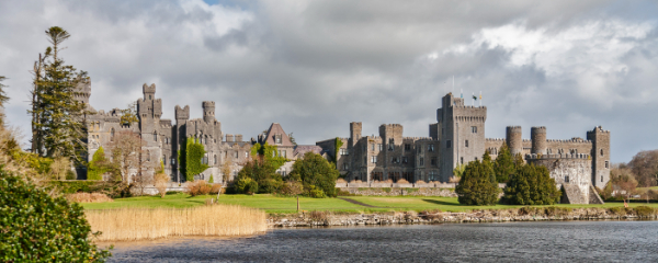 A medieval style castle with turrets in front of a lake